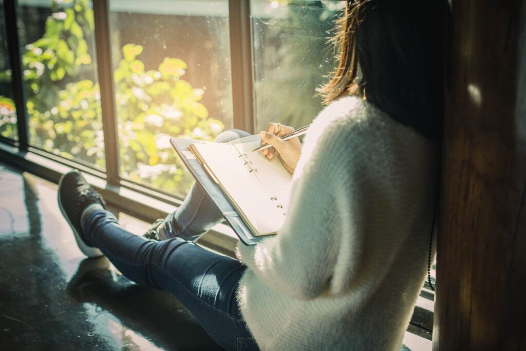 morning habits to boost energy -person journaling by window
