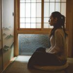 woman meditating near window