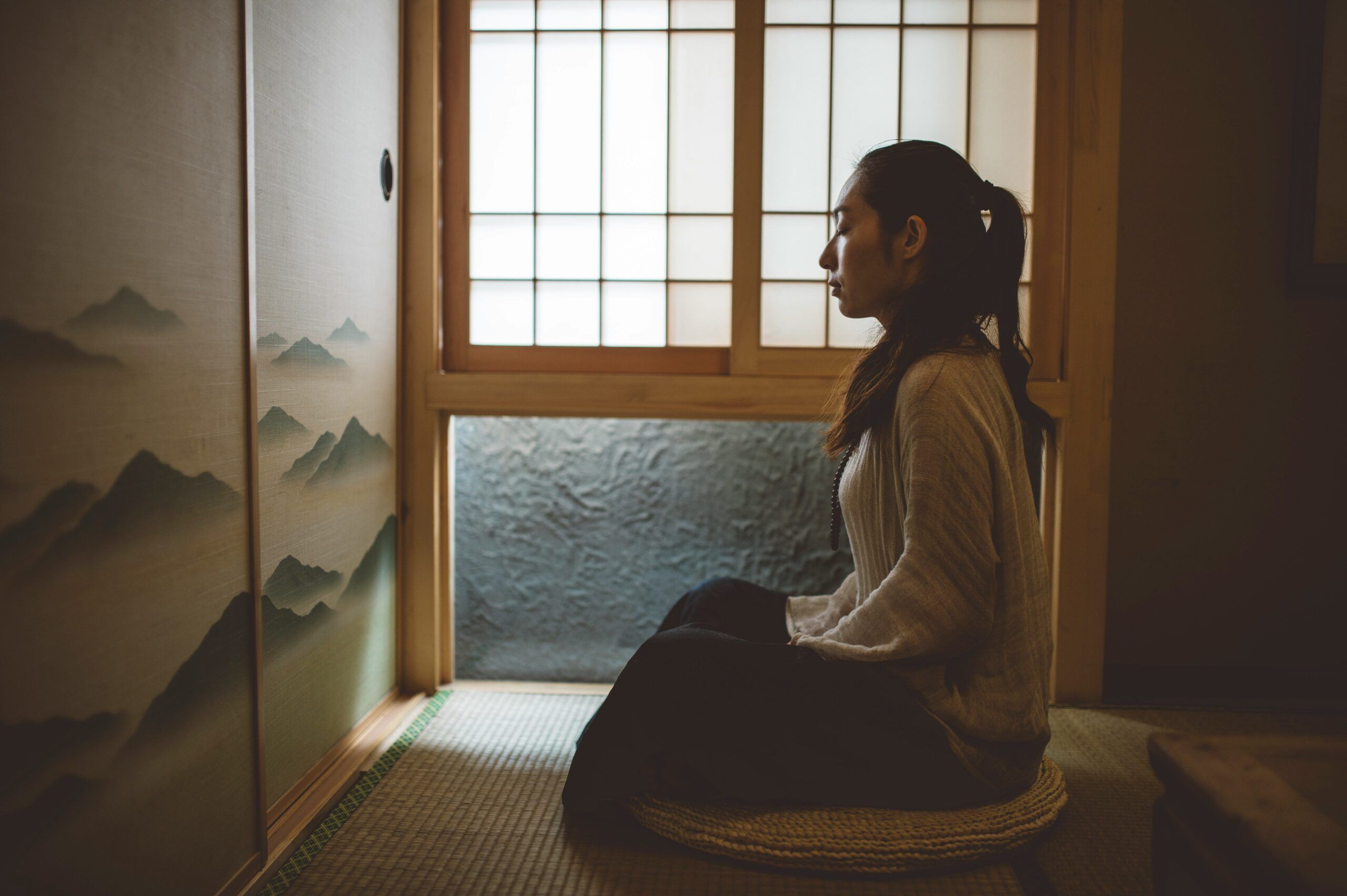 woman meditating near window